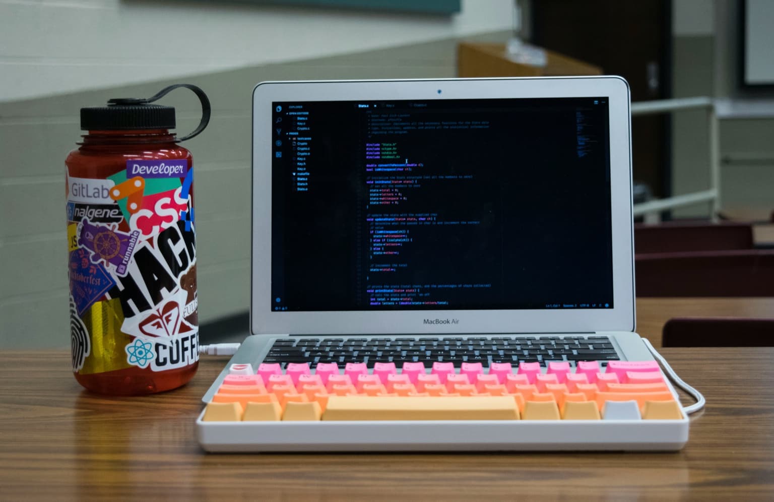 MacBook Air with an external mechanical keyboard while coding in a classroom
