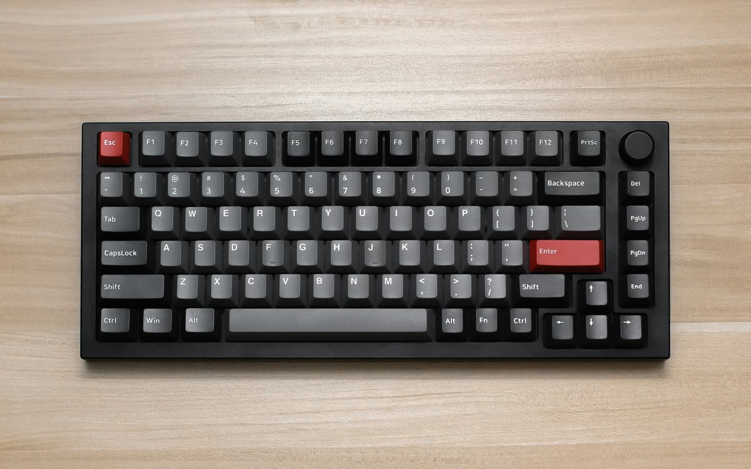 75% mechanical keyboard with gray keycaps and a red Enter key on a wooden desk