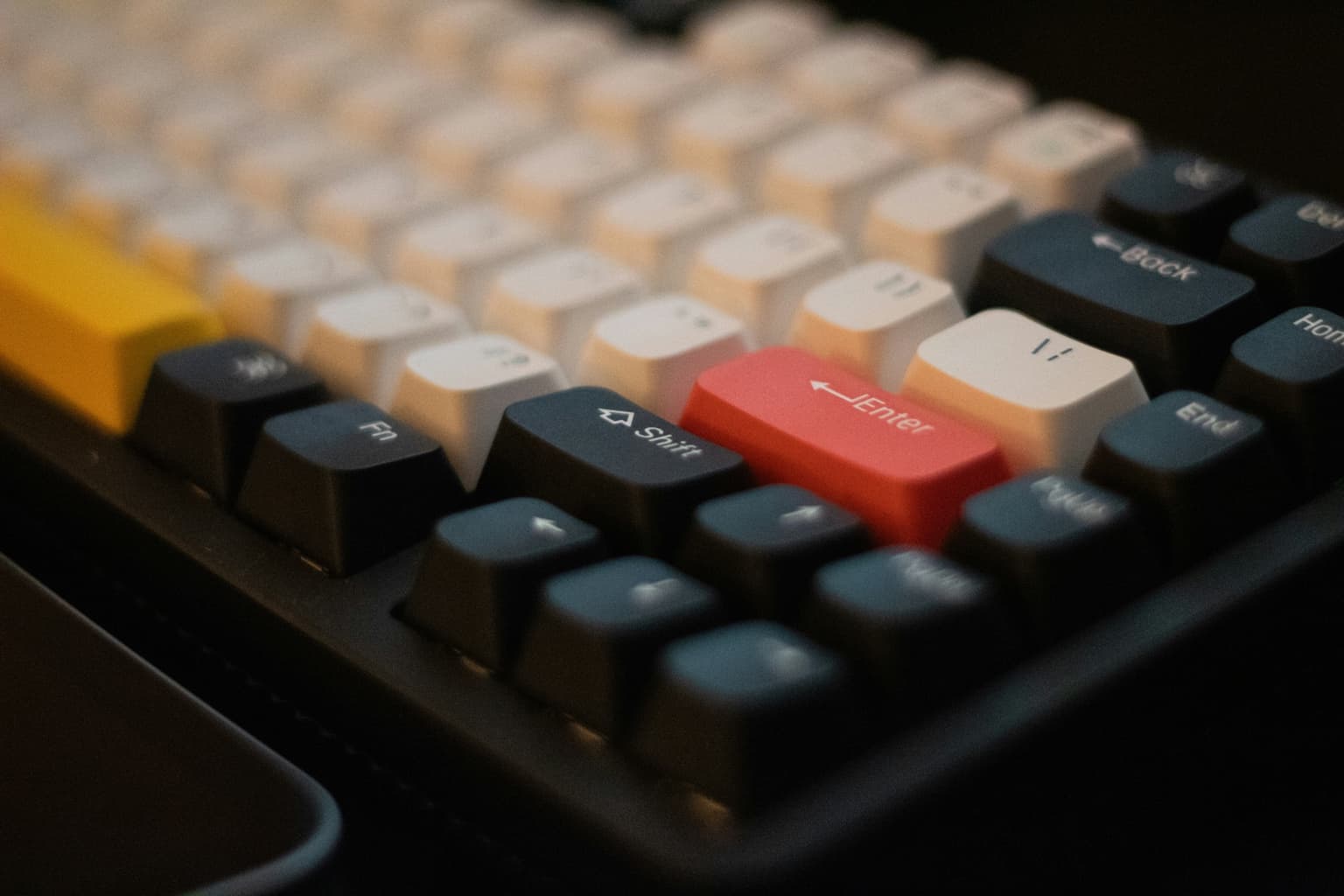 Close-up of a mechanical keyboard with a red Enter key and cream keycaps