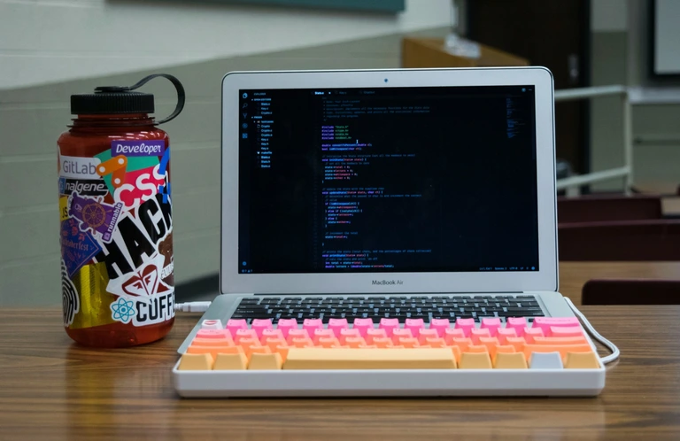 MacBook Air with an external mechanical keyboard while coding in a classroom