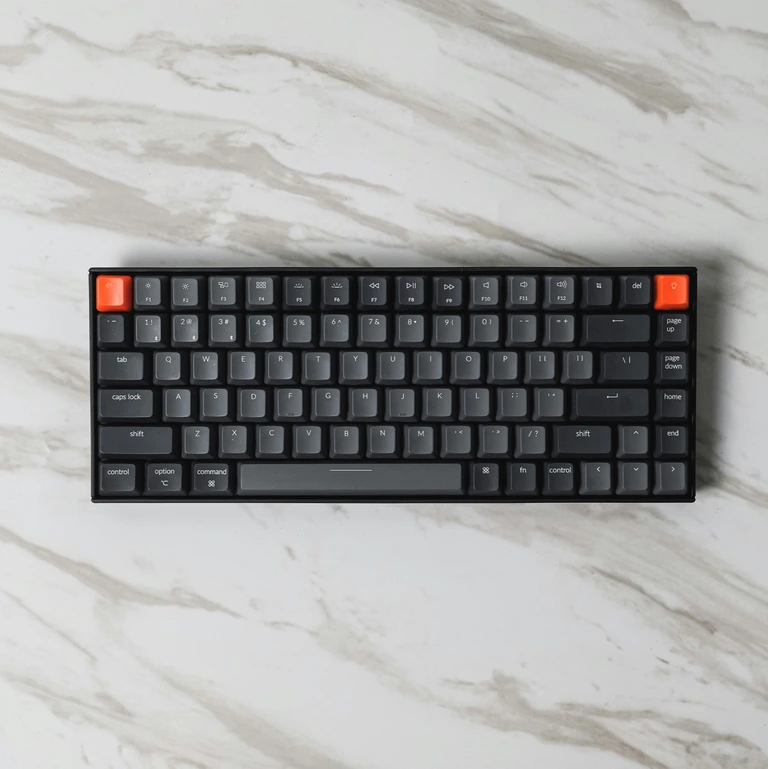 Compact mechanical keyboard with dark gray keycaps on a marble desk